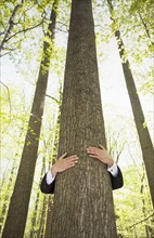 Man in suit hugging tree