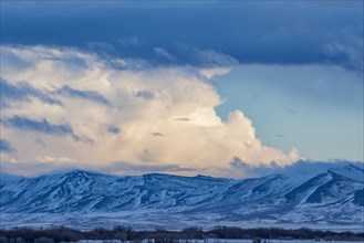 Snow dusted mountains and clouds over prairie