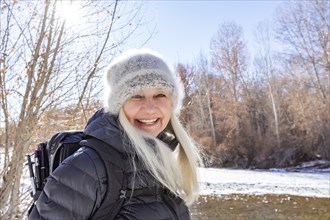 Winter portrait of smiling woman hiking along river