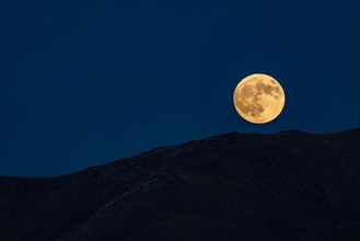 Full moon rising over hills