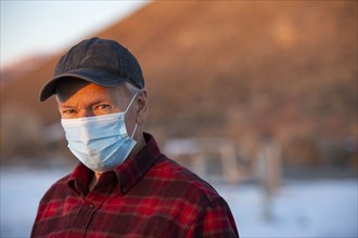 Outdoor portrait of senior man wearing COVID protective mask