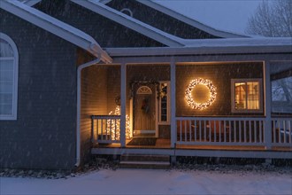 Porch decorated with Christmas lights during snow storm
