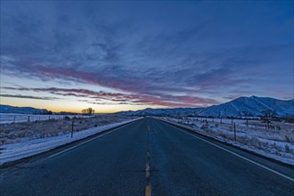 Pink dawn over rural highway and mountains