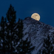 Full moon rising over Boulder Mountains in winter night