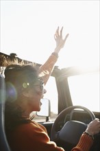 Hispanic woman raising arms while driving
