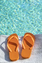 Orange flip flops on towel at poolside