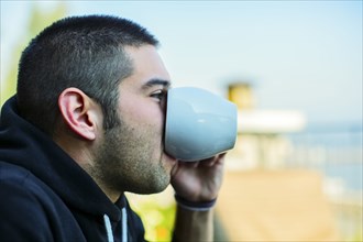 Hispanic man drinking cup of coffee