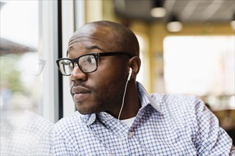 Black man listening to earphones in coffee shop