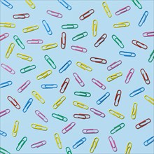 Multi colored paper clips scattered against blue background