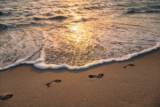 Footprints on beach at sunset