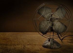 Old metal electric fan on wooden table