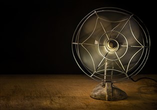 Old metal electric fan on wooden table