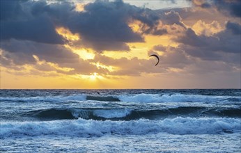 Kite surfer in ocean at sunrise