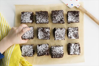 Overhead view of boys (6-7) hand reaching for freshly baked brownie