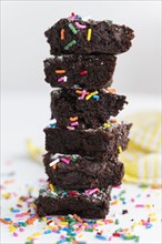 Stack of freshly baked brownies covered with colorful sprinkles