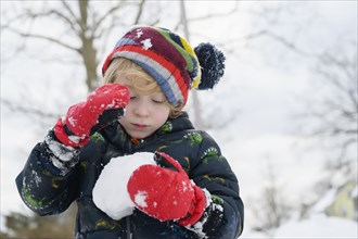 Boy (6-7) holding snowball