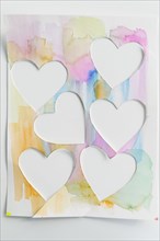 Studio shot of painted colorful paper with cut hearts