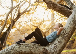 Girl relaxing on tree branch