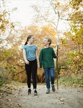 Boy and girl walking on footpath in forest