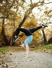 Girl doing handstand on footpath in forest