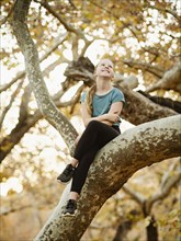 Girl sitting on tree branch