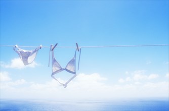 White bikini drying on clothesline above sea