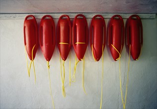 Row of red lifeguard floats hanging on wall