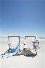 Empty beach chairs with bag and towel on beach