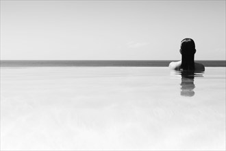 Rear view of woman in infinity pool