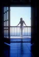 Rear view of woman standing on balcony of holiday villa by sea