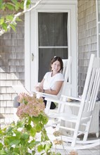 Portrait of smiling woman sitting on porch with laptop