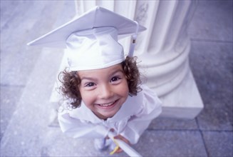 Portrait of girl in white graduation cap and gown