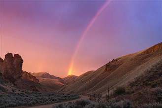 Rainbow above desert landscape at sunset