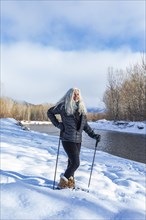 Senior woman with long white hair in snowshoeing in winter landscape