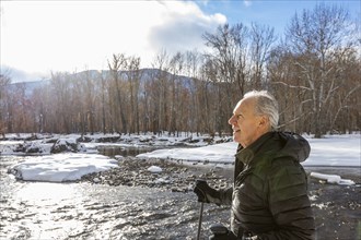 Senior man snowshoeing in winter landscape by river