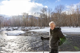 Portrait of senior man snowshoeing in winter landscape by river