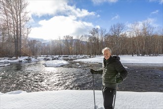 Portrait of senior man snowshoeing in winter landscape by river