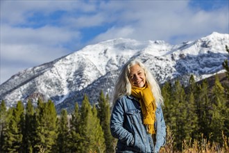 Portrait of smiling senior woman standing in autumn mountain landscape