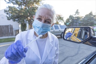 Healthcare worker reaching out with nasal swab for drive-thru coronavirus testing