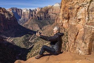 Senior man using phone at overlook of Zion Canyon in Zion National Park