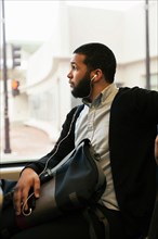 Young man traveling on light train wearing earphones