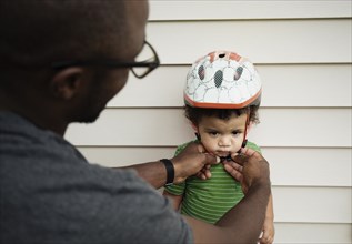 Father putting on helmet for son