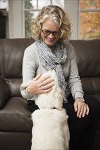 Senior woman with dog in living room