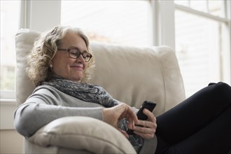 Senior woman relaxing on chair with mobile phone