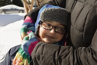 Mother hugging son wearing winter hat and glasses