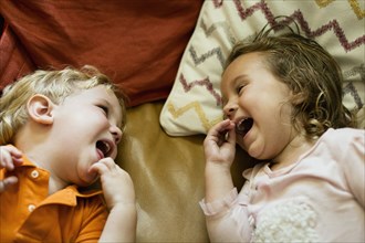 Male and female toddler friends giggling on sofa