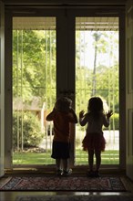 Male and female toddler friends silhouetted by patio door