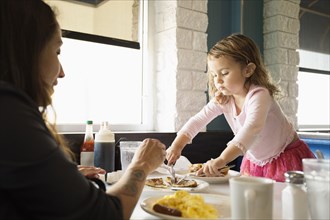 Mother and toddler daughter eating in diner