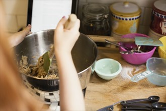 Over shoulder view of girls hand mixing in kitchen bowl