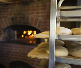 Artisan bread on shelves in kitchen with brick oven